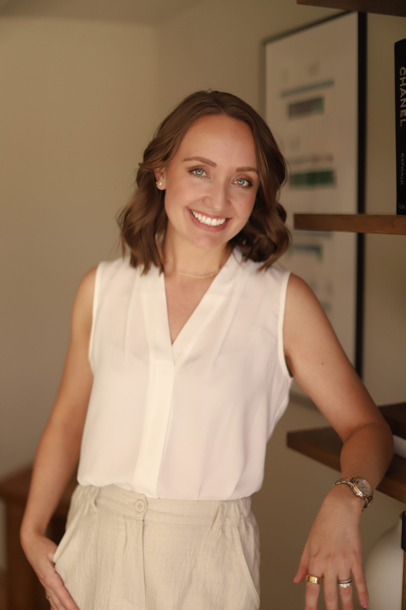 Danielle Duckett headshot - smiling and leaning against a bookshelf.